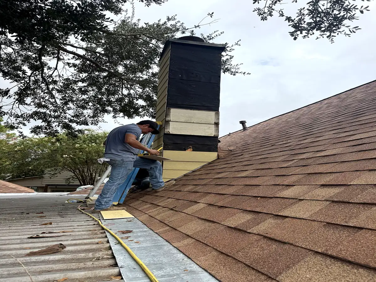 Roofline work beside a chimney on a shingled home